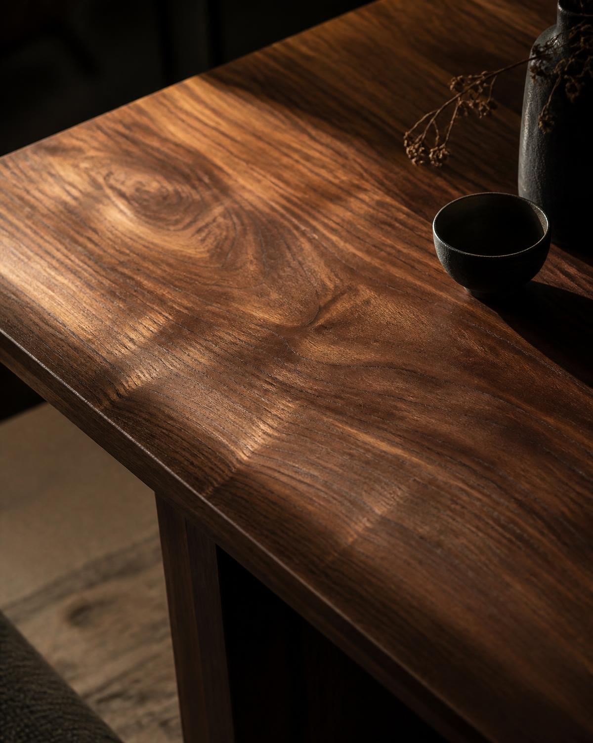 Raking light across the hand-planed surface of a solid walnut table, revealing the grain